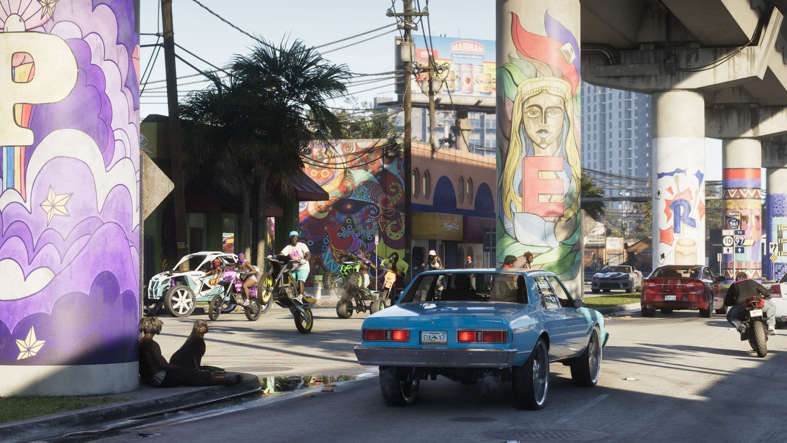 Riders on dirt bikes and ATVs pulling wheelies on a Vice City street under a mural-painted overpass